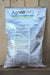 A large white bag of Agree WG Biological Insecticide standing upright against a light wood plank background. The bag features the 'Agree WG' at the top, along with extensive black and blue text and a caution label.