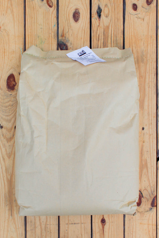 A folded beige kraft paper bag with a small white label at the top, placed on a light wood plank surface.