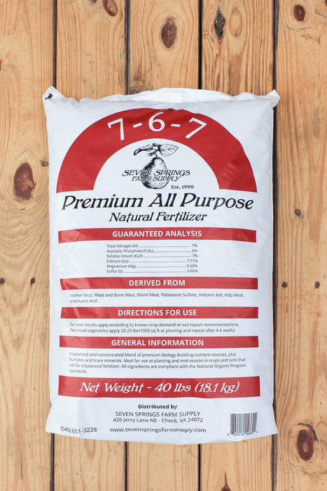 A 40 lbs bag of Seven Springs Farm Supply 7-6-7 Premium All Purpose Natural Fertilizer, displayed flat on a light brown wooden plank background.