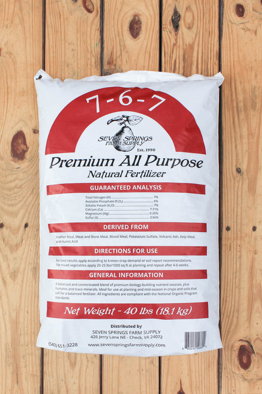 A 40 lbs bag of Seven Springs Farm Supply 7-6-7 Premium All Purpose Natural Fertilizer, displayed flat on a light brown wooden plank background.