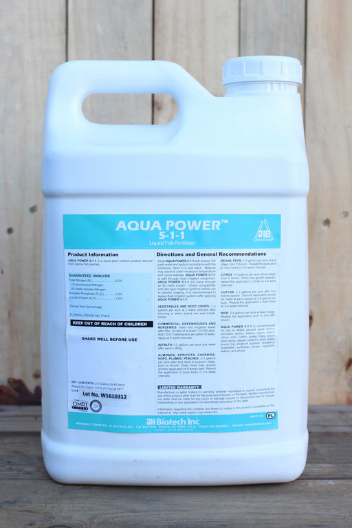 A large white plastic jug of Aqua Power 5-1-1 liquid fertilizer by JH Biotech Inc., set against a rustic wooden plank background.