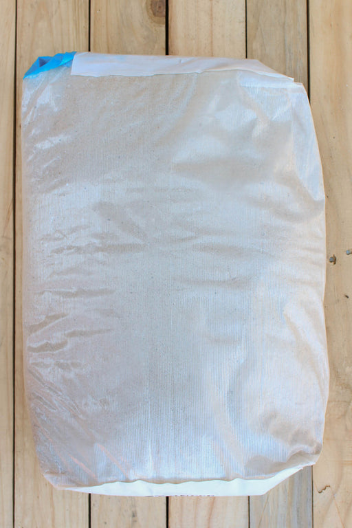 A large white woven sack or bag with a blue seal tape closure, photographed from above on a light-colored wooden plank surface.