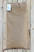 A brown paper bag of AWP, laid flat on a light-colored wooden plank surface.