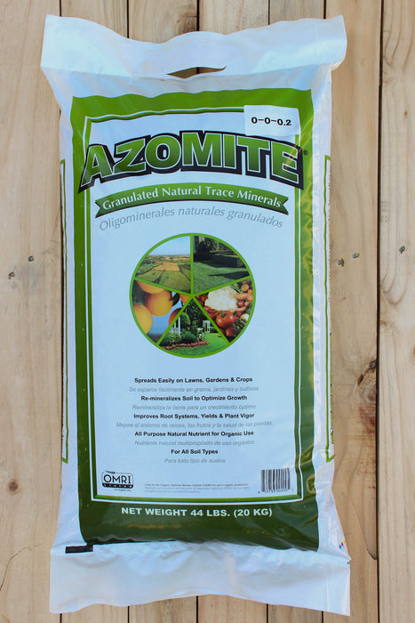 A 44 lb bag of Azomite Granulated Natural Trace Minerals fertilizer, displayed flat on a light-colored wooden plank surface. The packaging is white with a prominent green border and features the brand name 'AZOMITE' in bold green letters with a black outline.