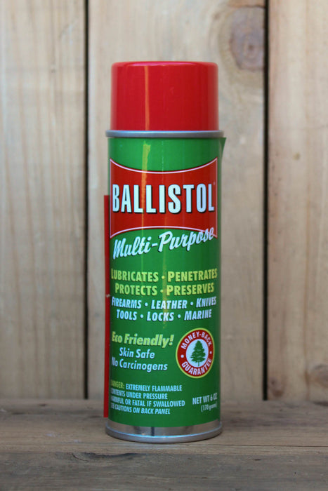 A can of Ballistol Multi-Purpose lubricant and protector spray, featuring a green label with a red cap, set against a rustic wooden background.