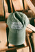 An olive green baseball cap with 'SEVEN SPRINGS FARM SUPPLY' embroidered in white on the front, resting on a stack of wooden pallets.