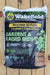A bag of Wakefield Biochar Blends Gardens & Raised Beds soil amendment, placed on a wooden plank surface. The packaging is black with green, yellow, and white text and graphics, showing a potted plant.