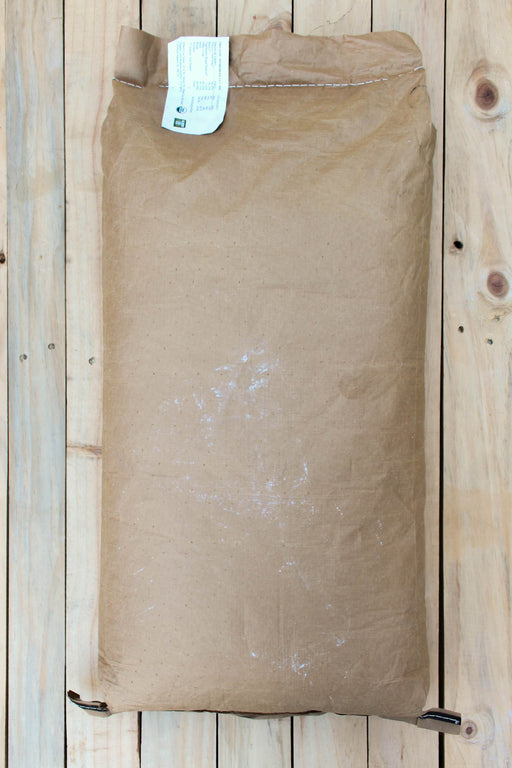 A large brown kraft paper bag with a white label at the top, placed on a light-colored wooden plank surface.