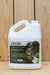 A white plastic jug of BioSafe Weed & Grass Killer herbicide with a detailed green and white label, set against a light wood plank background.