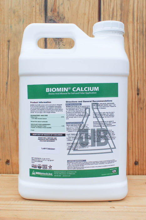 A white plastic jug of Biomin Calcium liquid fertilizer by JH Biotech Inc., featuring a green and white label, set against a rustic wooden plank background.