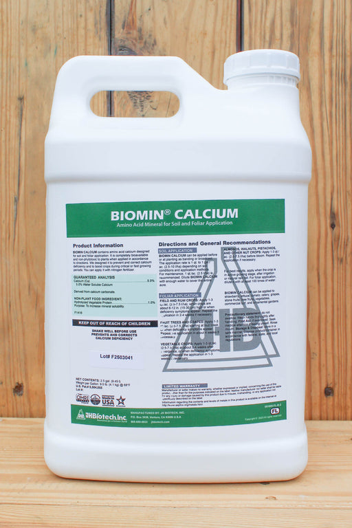 A white plastic jug of Biomin Calcium liquid fertilizer by JH Biotech Inc., featuring a green and white label, set against a rustic wooden plank background.