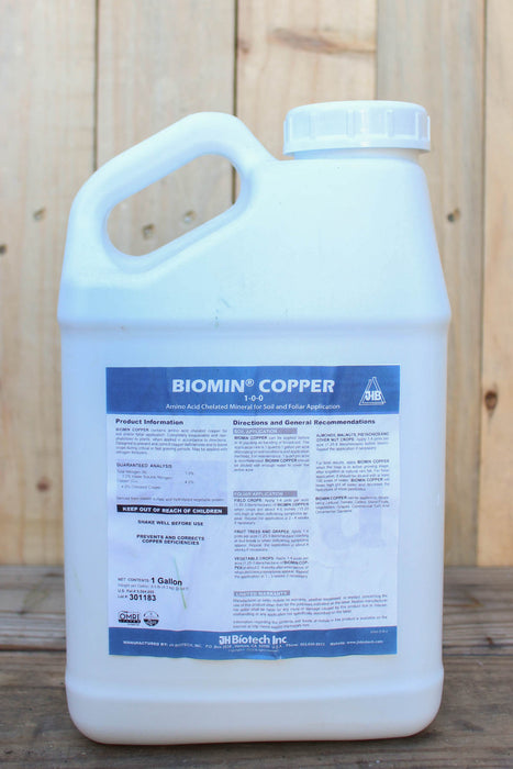 A large white plastic jug of Biomin Copper fertilizer with a blue and white label, set against a rustic wooden plank background.