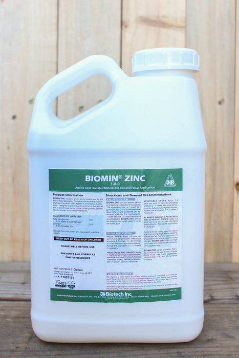 A large white plastic jug of Biomin Zinc 1 gallon bottle with a handle, standing on a wooden surface against a light wood plank background. The front label features green and black text and details.