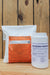 A white bag of Buffer Protect NT and a white plastic tub of Blossom Protect standing side by side on a wooden surface against a wooden plank background.