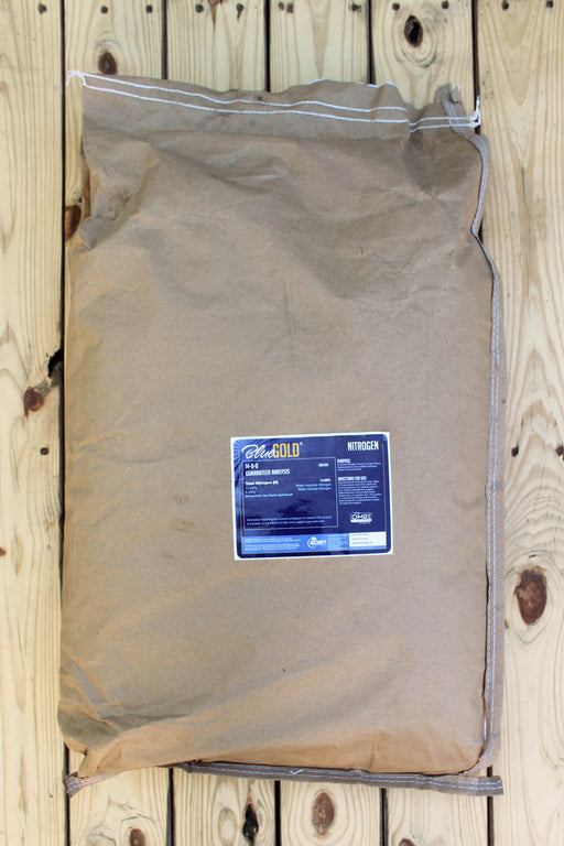 A large brown paper bag of BlueGold
 Nitrogen fertilizer lies on a light-colored wooden plank surface.