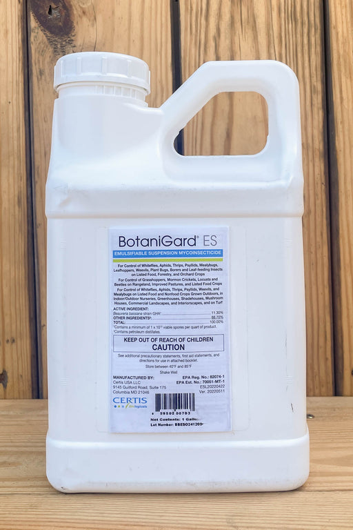 A white plastic jug of BotaniGard ES standing on a light wood surface against a darker wood plank background.