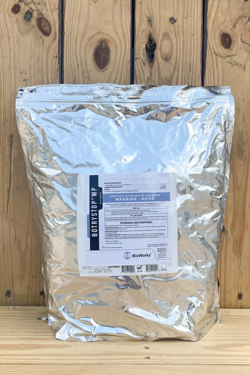 A large silver foil resealable bag of BotryStop WP standing upright against a rustic wooden plank background. A white product label is centered on the front of the bag.