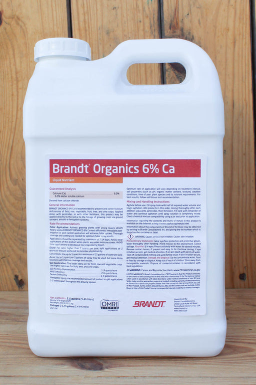 A large white plastic jug of Brandt Organics 6% Calcium liquid fertilizer, featuring a detailed white label with red and black text, set against a rustic wooden plank background.