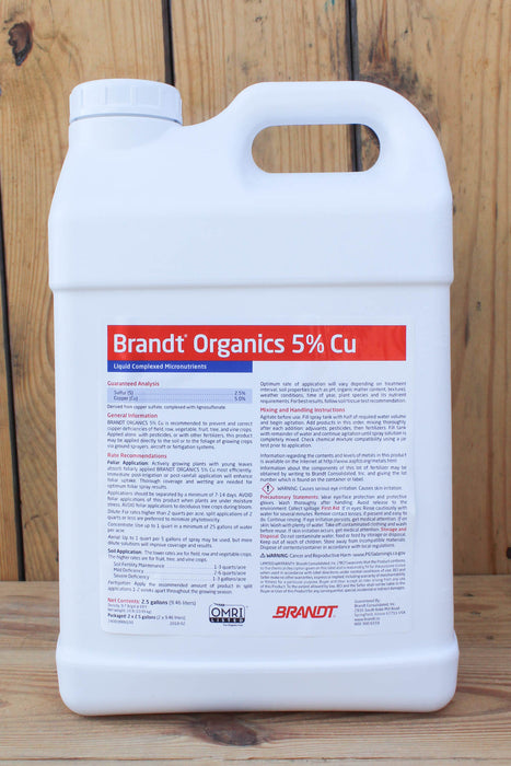 A large white plastic jug of Brandt Organics 5% Copper liquid micronutrients, standing against a rustic wooden plank background.