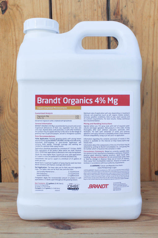 A large white plastic jug of Brandt Organics 4% Mg liquid fertilizer, standing upright against a rustic wooden plank background.