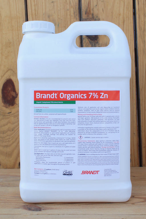A large white plastic jug of Brandt Organics 7% Zn liquid fertilizer, featuring a detailed white label with red and green text, set against a rustic wooden plank background.