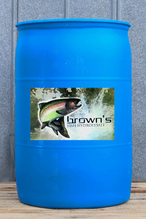 A large blue plastic barrel with a label for 'brown's FISH HYDROLYSATE' featuring a salmon graphic, set against a gray paneled wall and wooden floor.