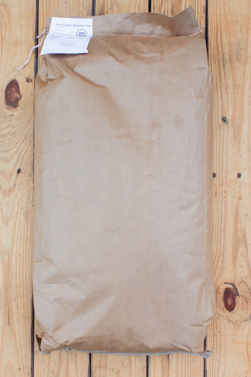 A brown kraft paper bag with a white paper tag attached, placed on a light wood plank surface.