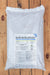 A large white plastic bag of Bug-N-Sluggo slug and grub control product, featuring a detailed label, placed on a wooden plank surface.
