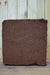 A rectangular brown coconut coir fiber block with rough, fibrous texture, standing upright on a wooden surface against a light wood plank background.