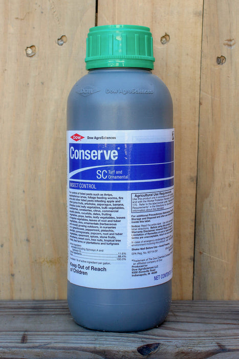 A bottle of Conserve SC turf and ornamental insect control, featuring a green cap and a blue and white label, set against a wooden plank background.