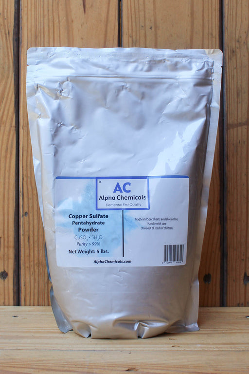 A 5 lb silver stand-up pouch of Alpha Chemicals Copper Sulfate Pentahydrate Powder, set against a rustic wooden plank background.