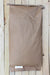 A brown paper bag with a crimped top edge and a small white label at the bottom, laid flat on a light wood plank background.