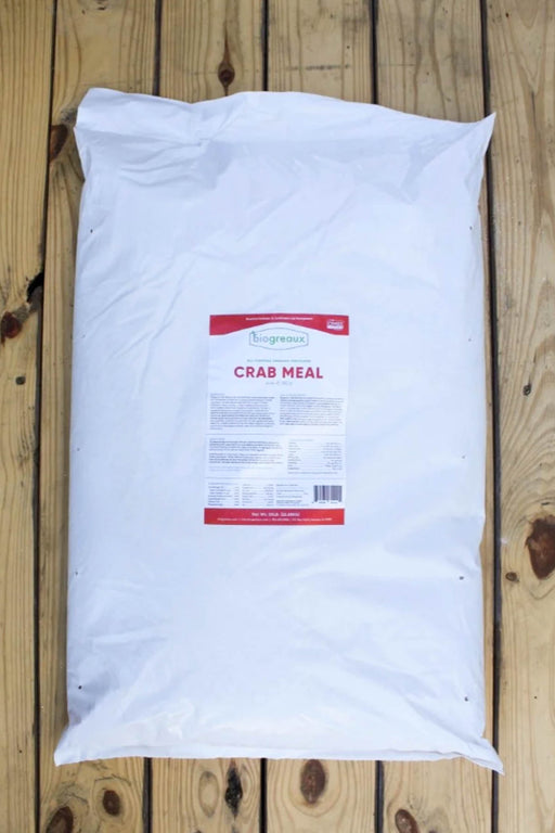 A large white bag of Crab Meal placed on a wooden plank surface.