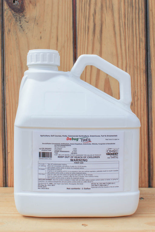 A large white plastic jug of Debug TRES liquid pesticide, featuring a detailed warning label, set against a rustic wooden plank background.