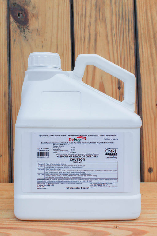 A white plastic jug of Debug Bug Turbo liquid pesticide with a handle and a detailed white label, set against a rustic wooden plank background.