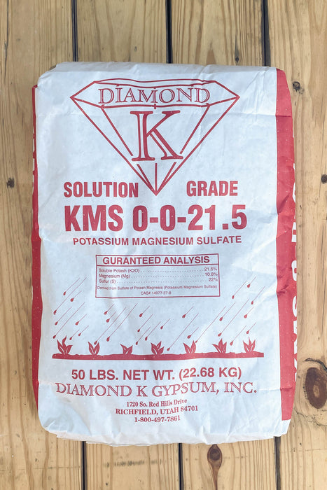 A 50 lb bag of Diamond K KMS 0-0-21.5 potassium magnesium sulfate, displayed on a light-colored wooden plank surface.