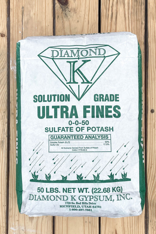 A 50 lb bag of Diamond K Ultra Fines Solution Grade SOP on a light brown wooden plank background.