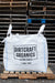 A large white bulk bag of Dirtcraft Organics Living Soils, 1 cubic yard, displayed on a wooden pallet in front of a stack of wooden pallets.