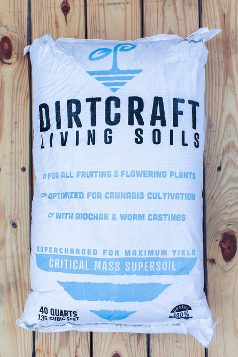 A 40-quart white bag of Dirtcraft Living Soils Critical Mass Supersoil, displayed flat on a rustic wooden plank background.