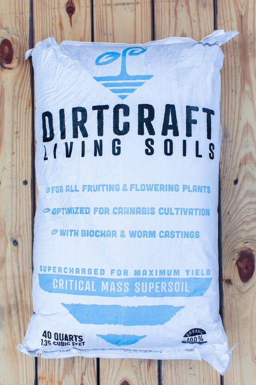 A 40-quart white bag of Dirtcraft Living Soils Critical Mass Supersoil, displayed flat on a rustic wooden plank background.