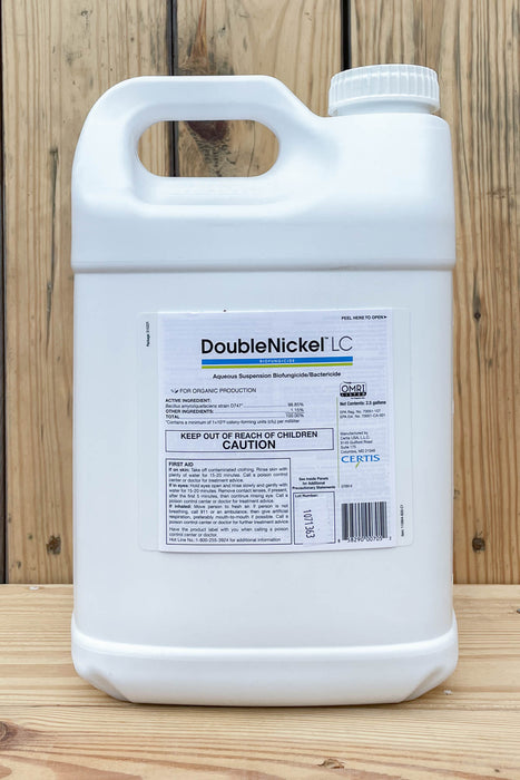A large white plastic jug of DoubleNickel LC with a handle and ribbed cap, standing on a wooden surface against a wooden plank background.