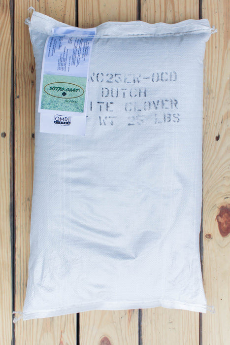 A 25 lb white woven sack of NITRO-COAT Dutch Clover Seed, placed on a light-colored wooden plank surface.