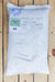 A 25 lb white woven sack of NITRO-COAT Dutch Clover Seed, placed on a light-colored wooden plank surface.