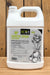 A white plastic jug of Eco-1 Garden Spray Concentrate with a handle, standing on a wooden surface against a wooden background. The label features black and white illustrations of a rose and tomatoes, along with green and black branding.
