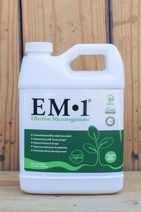 A white plastic quart of EM-1 Effective Microorganisms concentrated microbial inoculant, featuring a green and white label, set against a rustic wooden plank background.