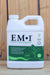 A white plastic quart of EM-1 Effective Microorganisms concentrated microbial inoculant, featuring a green and white label, set against a rustic wooden plank background.