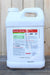 A 2.5 gallon white plastic jug of Brandt Ecotec Plus, standing on a dark wooden surface against a light wood plank background.