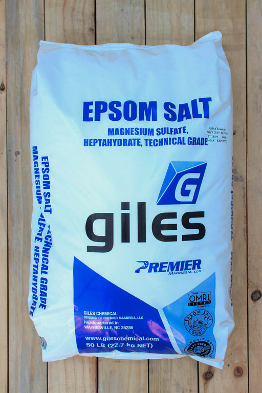 A 50 lb bag of GILES EPSOM SALT Premier Technical Grade magnesium sulfate, heptahydrate, shown on a light-colored wooden plank background.
