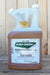 A gallon jug of MKG EverGreen Pyrethrum Concentrate, filled with amber-brown liquid, set against a rustic wooden plank background.