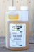A bottle of MGK EverGreen Pyrethrum Concentrate insecticide, showing the amber liquid and white cap against a rustic wooden background.
